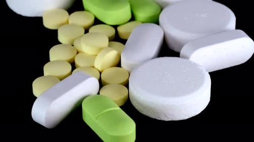Pills and medicines in close-up on a black background. Tablets and medicines in white, green color