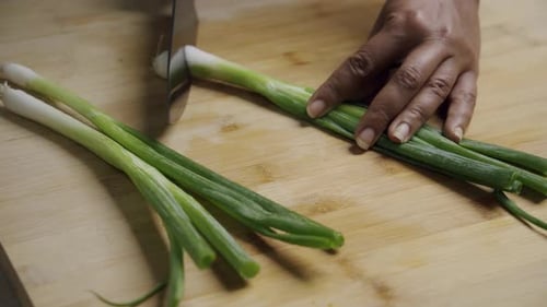 Chef Thinly Slicing Fresh Green Onions for Garnishing a Healthy Dish