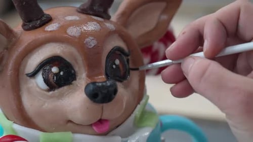 Close-up of a reindeer sculpture's eye being painted with precision using a fine brush