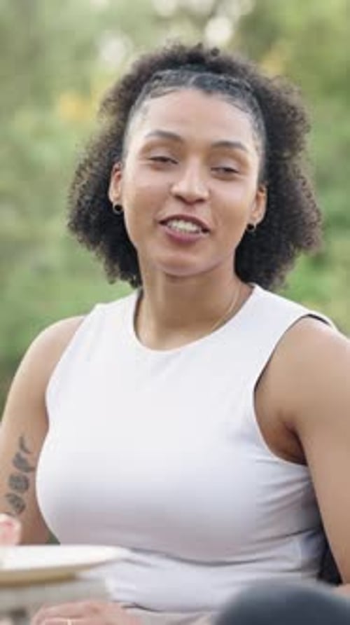 Happy Young Woman Laughing and Talking with Friends at a Park Picnic