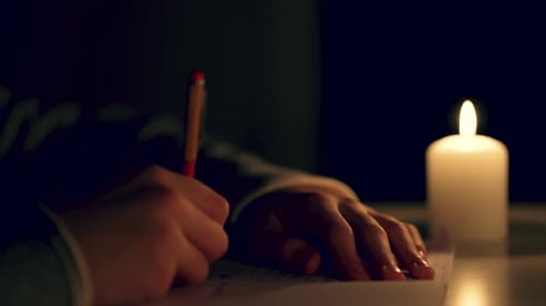 Schüler wtitng Fernunterricht zu Hause ohne Licht bei Kerzenlicht im dunklen Raum aus nächster Nähe