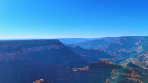 Grand Canyon cliffs under sun. Sunlit canyon walls showcase natural rock colors and depth.