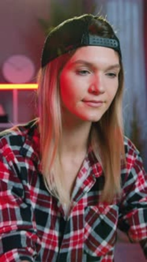 Une fille tendance de 25 ans, agréable, qualifiée et positive, vêtue de vêtements décontractés et d'une casquette, posant devant la caméra avec