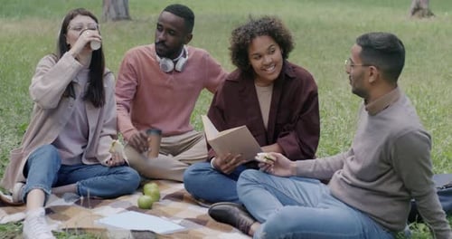 Group of Students Studying Outdoors in Park Drinking Coffee Talking and Reading Books Sitting on