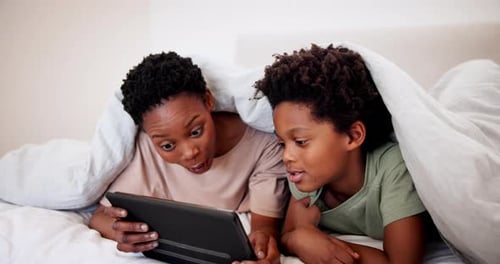 Mother and Child Use Tablet Under Blanket