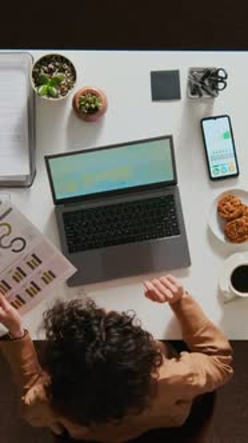 Female Manager Analysing Documents and Entering Data on Laptop at Office Table
