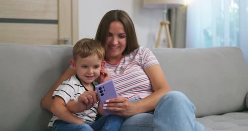 Mother and Son Using Phone on Couch Indoors