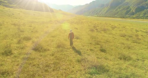 Flight Over Backpack Hiking Tourist Walking Across Green Mountain Field