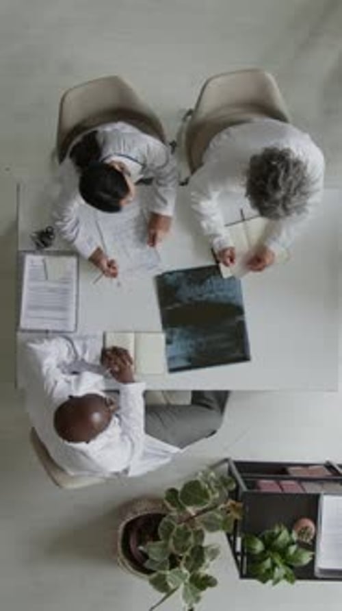 Vertical of Multiethnic Doctors Participating in Staff Meeting in Clinic Office