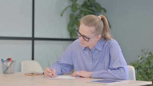 Woman Writing at Desk in Office