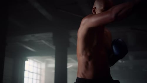 Powerful Man Boxing Training in Sport Loft Club. Close Up Male Fighter
