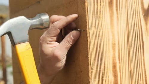 Fingernägel mit Hammer von Hand zur Sicherung der Rückwand eines Holzschranks aus Hartfaserplatte