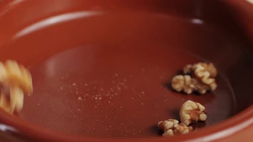 Walnut Halves Falling Into a Bowl