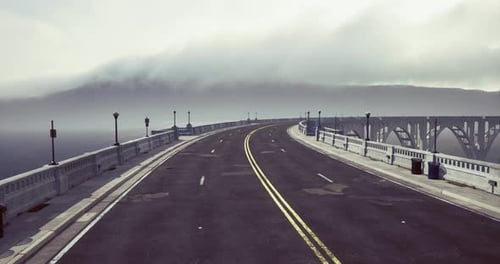 Manhã nebulosa em uma estrada sinuosa em uma ponte costeira em uma paisagem serena