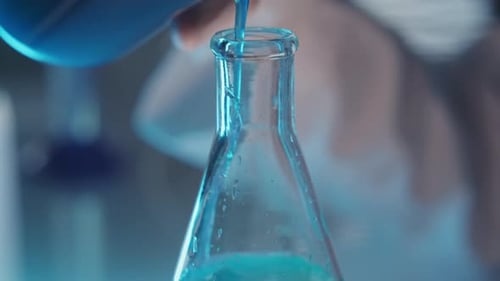 Close Up of Pouring Blue Liquid into Laboratory Flask during Research