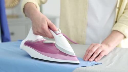 Woman ironing shirt on board at home, closeup