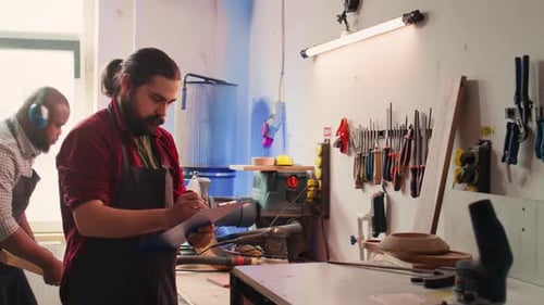 Craftsperson Drawing Blueprints in Studio Next to Coworker