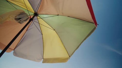 Colorful Beach Umbrella Gently Waving Under Blue Sky
