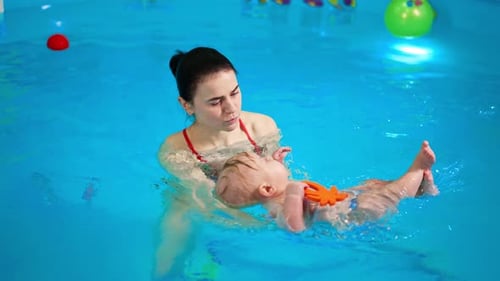 Sweet Caucasian infant baby lies on the water in the swimming pool.