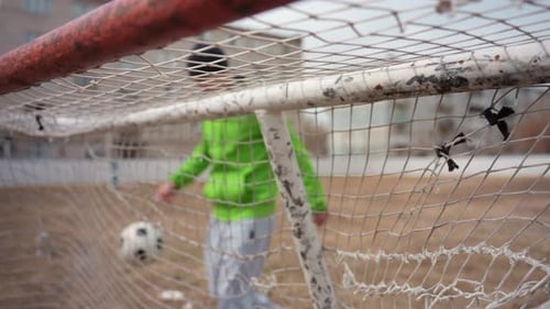 Young Man Kicks Soccer Ball Into Goal