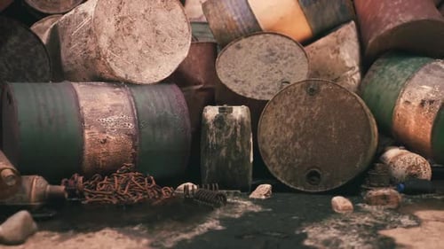 Rusty Barrels and Debris Scattered Across a Desolate Landscape Near a River