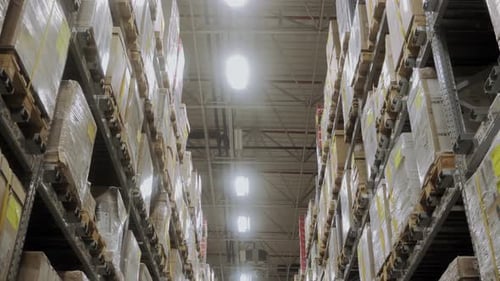 The Camera Moves Between Rows in a Warehouse Filled with Boxes