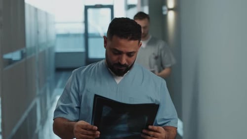 Portrait of Male Doctor with X-Ray in Hospital Corridor