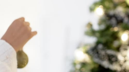 Woman Decorating Christmas Tree with Gold Ornament