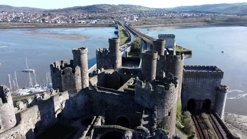 Medieval Conwy castle Welsh market town ruins aerial flyover view of historical harbour bridge