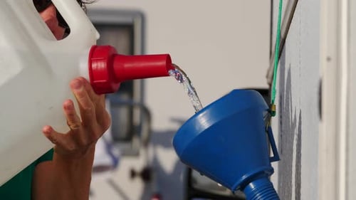 Pouring water into blue funnel from jug