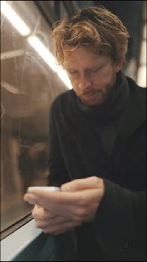 Young Man Using Smartphone While Commuting on Subway Train