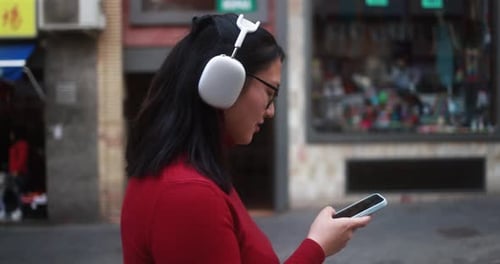 Woman Listens with Headphones While Using Phone