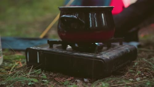 Close Up of Black Cooking Pot on Gas Stove During Outdoor Forest Camping