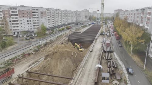 La excavadora opera en un pozo profundo del metro rodeado de edificios