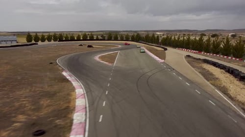 A dinamic drone shot of racing cars moving towrds the camera on a race circuit.