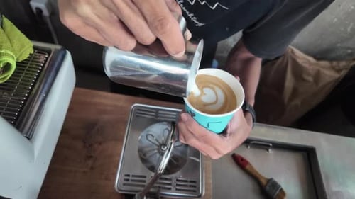 Barista doing cappuccino heart shape art in coffee shop