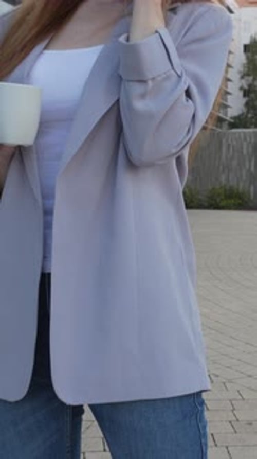 Woman on Mobile Phone Holding Coffee Outdoors