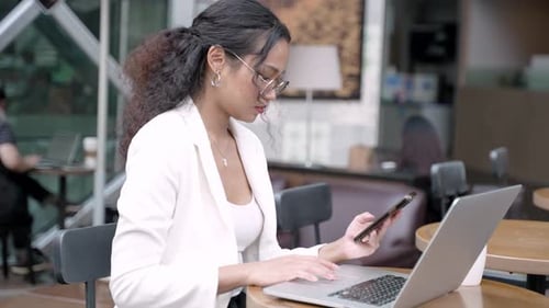 Professional Asian Businesswoman Using Mobile Phone at Cafe Table