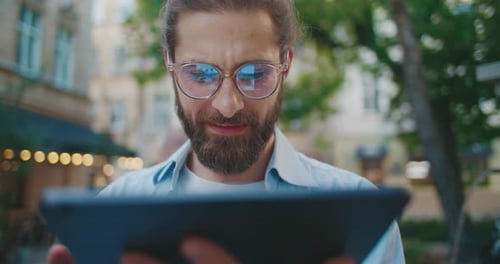 Nahaufnahme eines selbstbewussten, stilvollen jungen Geschäftsmannes, der ein Fintech-Gerät verwendet, um an modernem Gadget Calm zu arbeiten