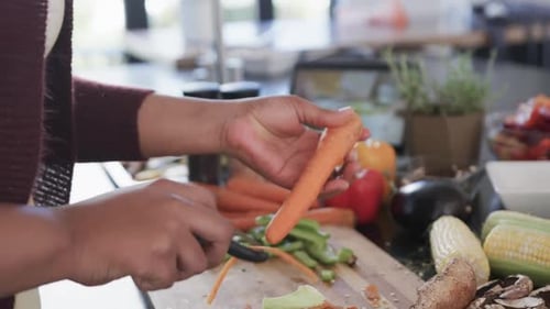 Person Peeling a Carrot in Bright Kitchen