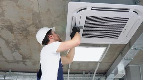 Man Installing New Air Conditioning Unit at Workplace