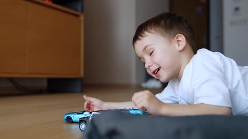 Smiling Boy Playing with Toy Cars on Floor
