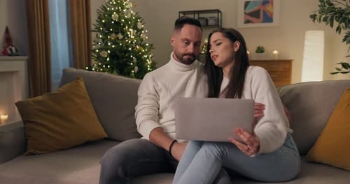Couple Using Laptop on Sofa at Christmas Time