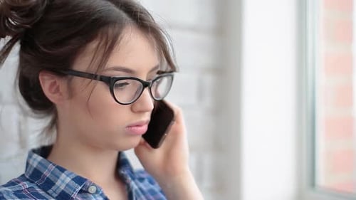 Woman Talking on Phone Indoors Wearing Glasses