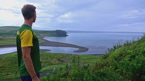 Man Looks at Beautiful Horizon with Coast in Summer Clip Man Stands on Hill Overlooking Beautiful