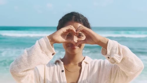 Joven mujer india optimista hace un gesto con el corazón y mira a la cámara