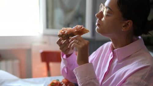 Young Woman Enjoys Prosciutto Sandwich Indoors