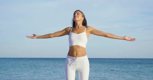 Beautiful woman doing yoga at sea, harmony and freedom, background of the sea and sand, concept of