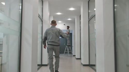 Technician Installing Security Camera with Supervisor Directing