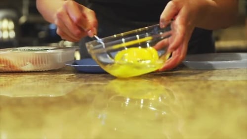 close up shot of a female mixing eggs in a bowl as part of preparing ingredients to start cooking